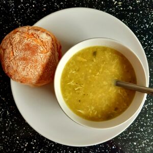 a picture of leek and courgette soup in a bowl, served with a ciabatta