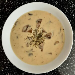 a bowl of cremay potato and mushroom sauce with parsley garnish on top