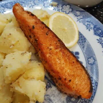 a picture of salmon fillet served with potatoes and lemon