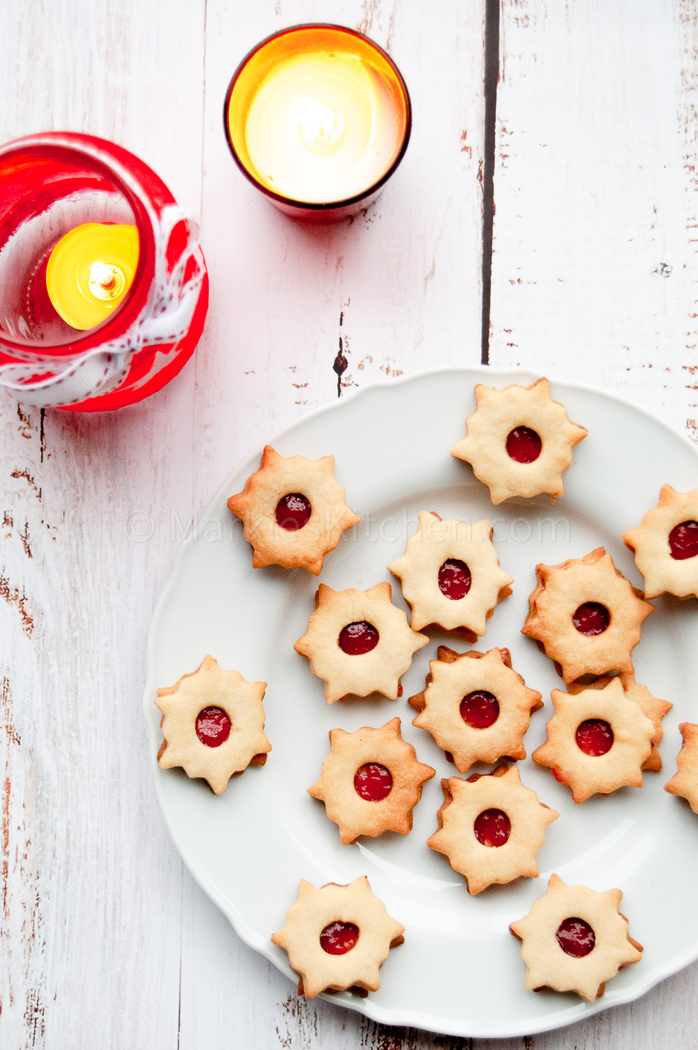 serving sugegstion: linzer cookies on a plate next to two candles