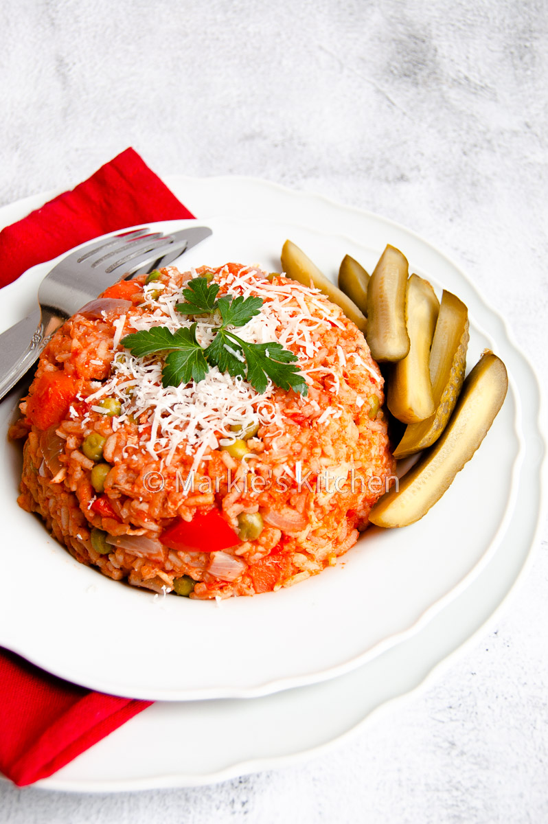 chicken, tomato and rice casserole served on a plate, with grated cheese and gherkins