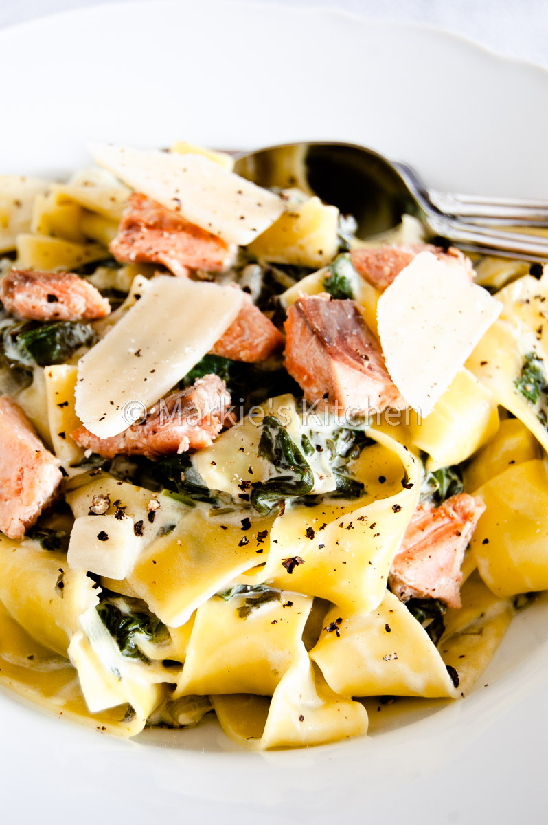 A close up picture of pasta with creamed spinach, salmon and grated cheese