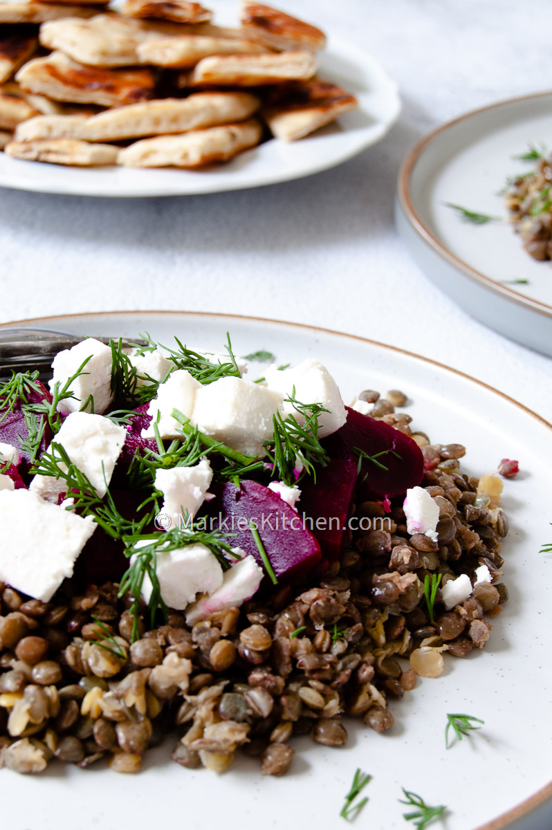 a close-up picture of lentil beetroot and feta salad served with Greek style pita bread