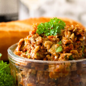 A close up photo of sundried tomato spread in a glass bowl, served with parsley