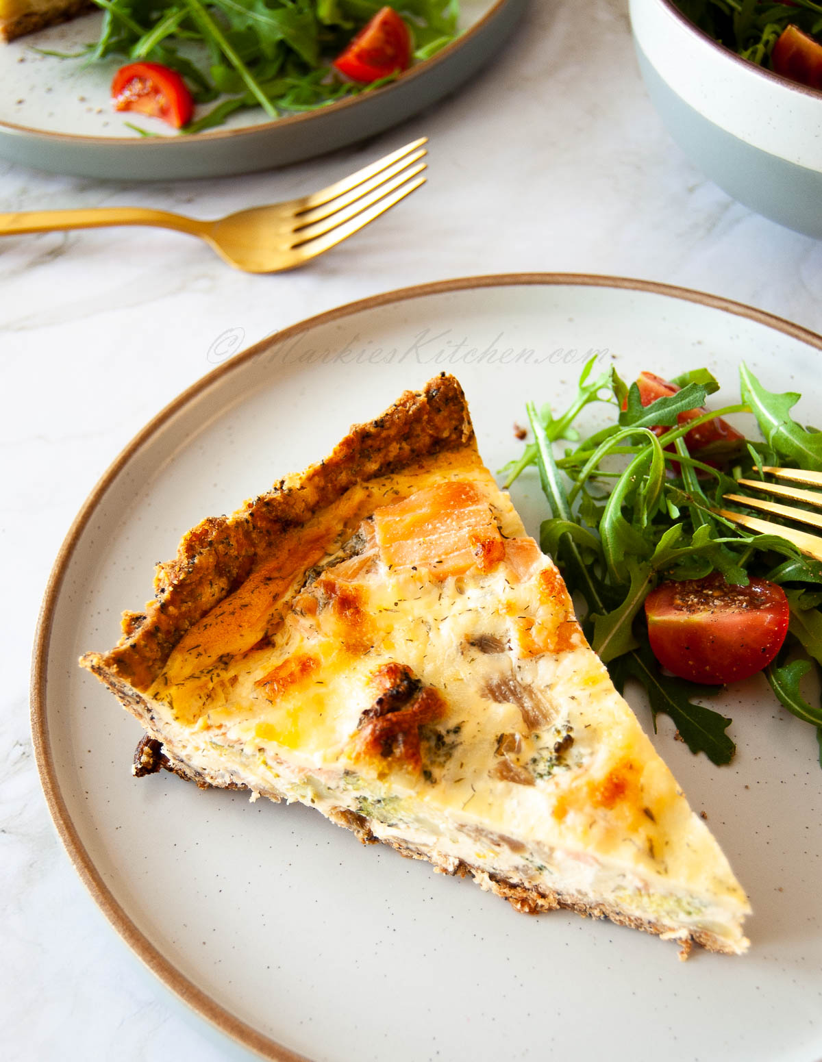 A photo of a portions of quiche and a salad on a plate.