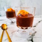 A photo of two goblets with chocolate mousse, decorated with a skin of orange.